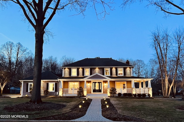 view of front of property with a porch, aphalt driveway, a front yard, and a chimney