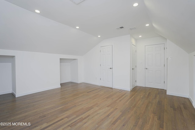 additional living space featuring visible vents, wood finished floors, recessed lighting, baseboards, and vaulted ceiling