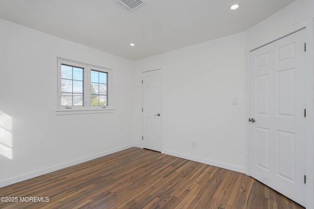 empty room with visible vents, recessed lighting, baseboards, and dark wood-style flooring