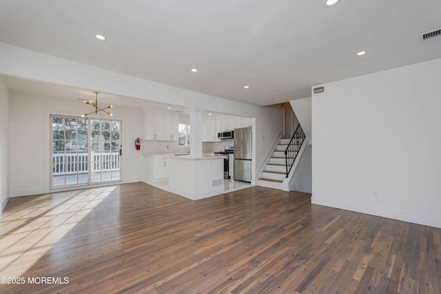 unfurnished living room with stairway, recessed lighting, an inviting chandelier, and hardwood / wood-style floors