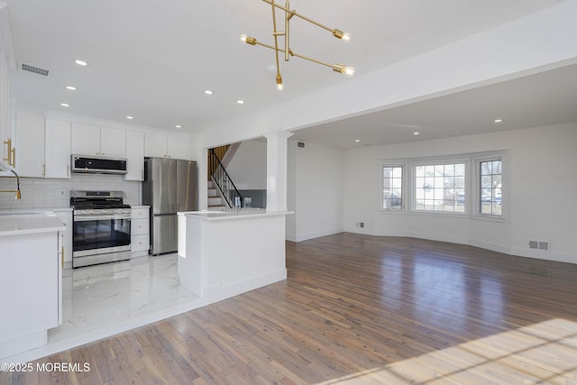 kitchen featuring stainless steel appliances, backsplash, visible vents, and open floor plan