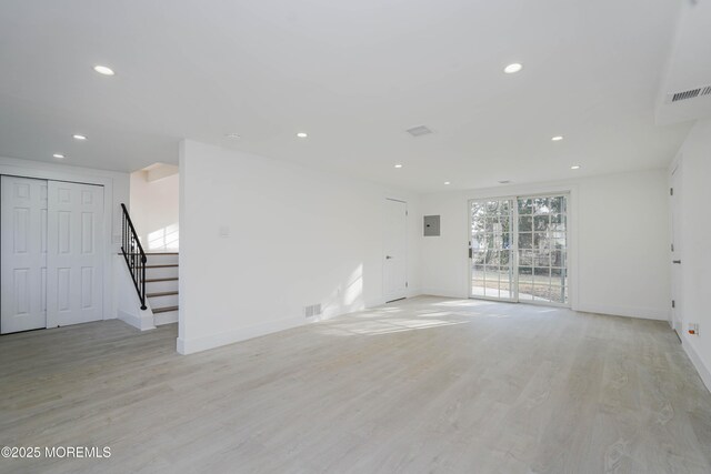 unfurnished living room with light wood-type flooring, visible vents, recessed lighting, stairway, and baseboards