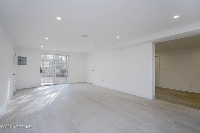 unfurnished room with light wood-type flooring, visible vents, electric panel, recessed lighting, and baseboards