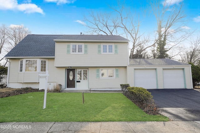 tri-level home with a shingled roof, a front lawn, an attached garage, and aphalt driveway