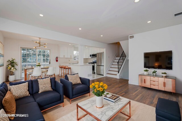 living room with a chandelier, stairway, recessed lighting, and wood finished floors