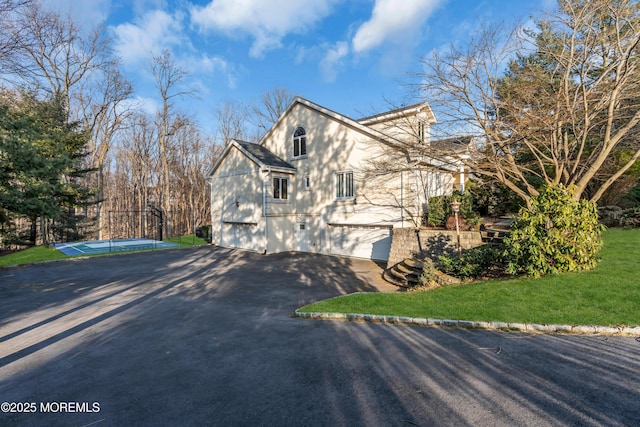 view of side of home featuring a lawn, driveway, a garage, and fence