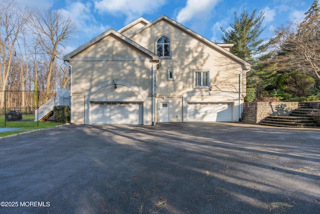 view of side of home featuring stairway, a garage, and driveway