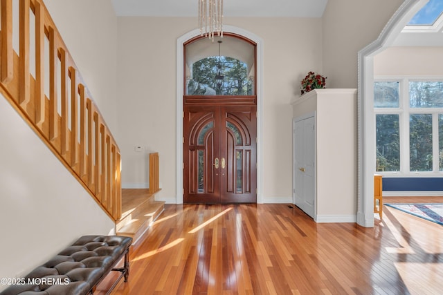 entryway with stairway, a high ceiling, light wood-style floors, and baseboards