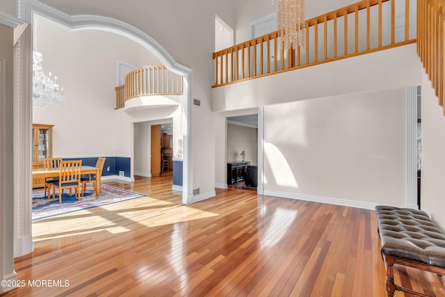 living room featuring baseboards, wood-type flooring, a notable chandelier, and a towering ceiling