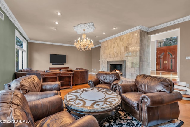 living room with light wood-style flooring, recessed lighting, ornamental molding, a tiled fireplace, and a chandelier