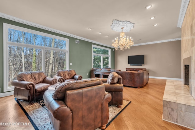 living room featuring baseboards, light wood-type flooring, an inviting chandelier, and ornamental molding