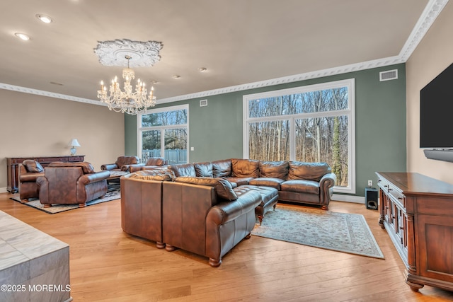 living area featuring an inviting chandelier, light wood-style flooring, visible vents, and ornamental molding