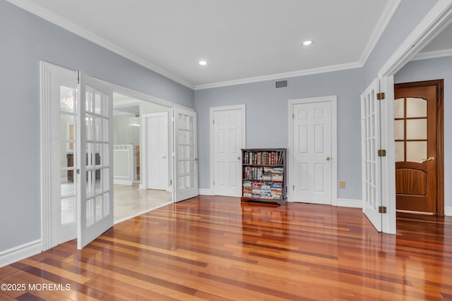 empty room with wood finished floors, visible vents, baseboards, french doors, and crown molding