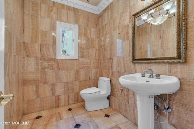 bathroom featuring tile patterned flooring, tile walls, toilet, and crown molding