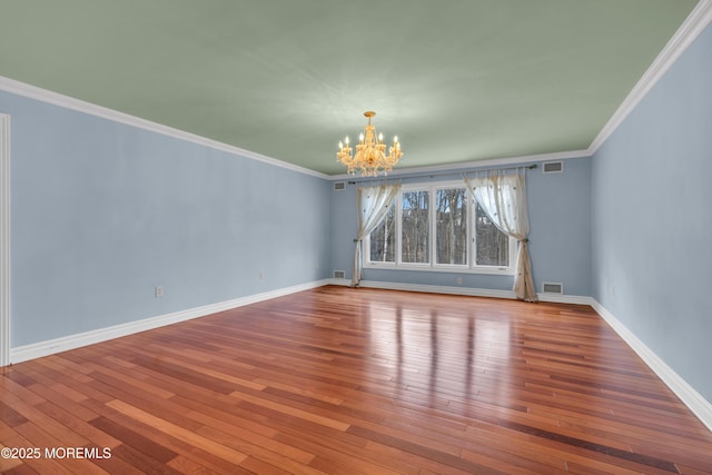 spare room featuring visible vents, crown molding, baseboards, a chandelier, and hardwood / wood-style flooring