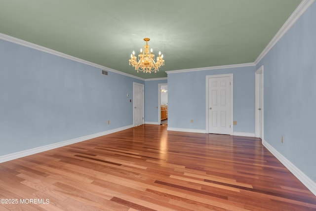 empty room featuring visible vents, ornamental molding, wood finished floors, baseboards, and a chandelier