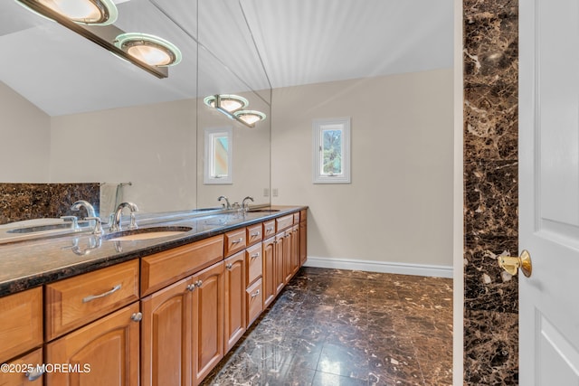 full bathroom with a sink, baseboards, and double vanity