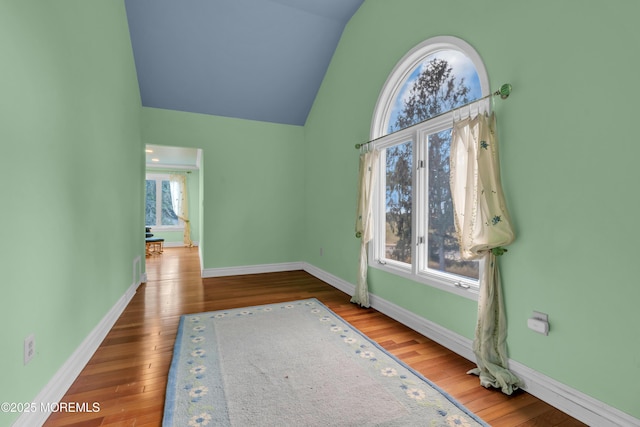 unfurnished room featuring vaulted ceiling, baseboards, and hardwood / wood-style floors