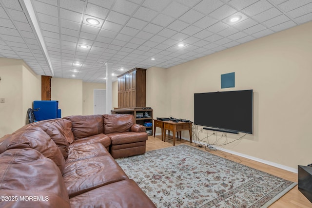 living room featuring recessed lighting, a drop ceiling, baseboards, and wood finished floors