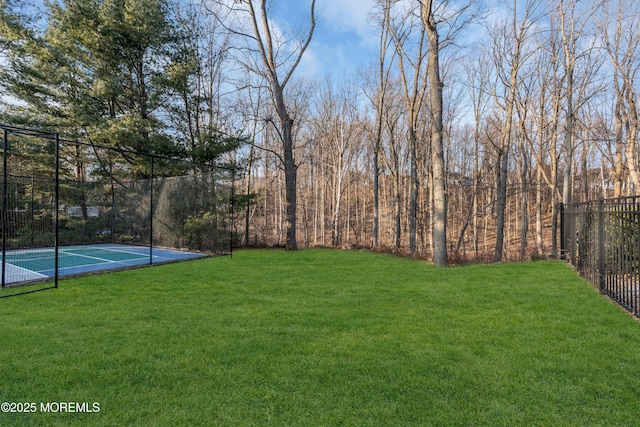 view of basketball court with a yard and fence