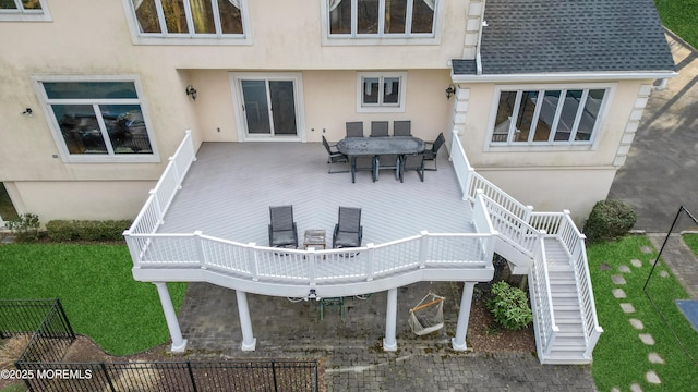 rear view of property featuring stucco siding, a deck, and outdoor dining space