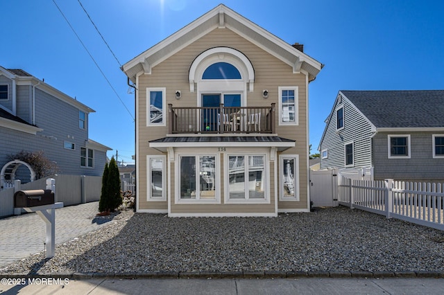 rear view of property featuring a gate, a balcony, and fence