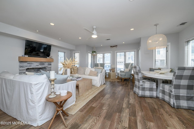 living room featuring recessed lighting, visible vents, a stone fireplace, and wood finished floors