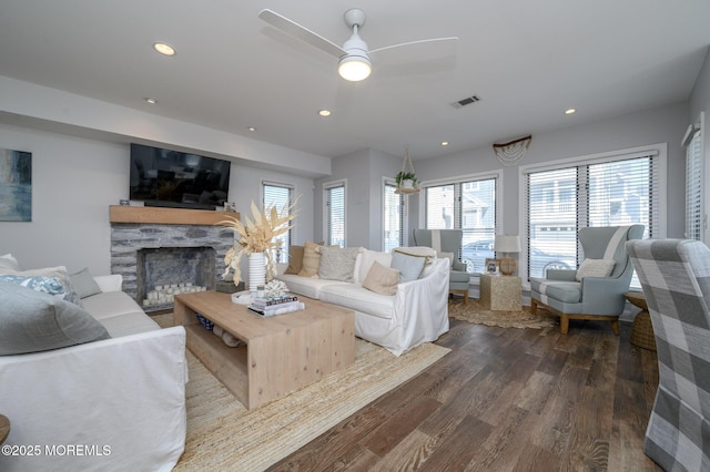 living area with recessed lighting, visible vents, a stone fireplace, and dark wood finished floors