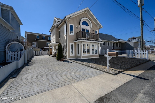 view of front of home featuring a fenced front yard, a balcony, and a gate