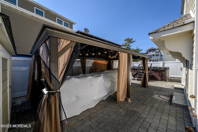 view of patio with a hot tub and fence