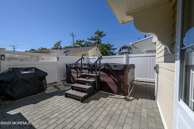 view of patio featuring grilling area, a fenced backyard, and a hot tub