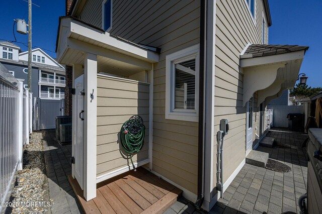 entrance to property with central air condition unit and fence