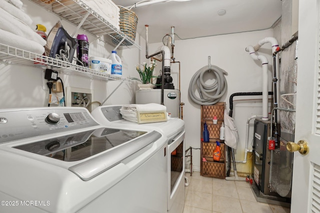 washroom with water heater, light tile patterned flooring, laundry area, and washer and clothes dryer