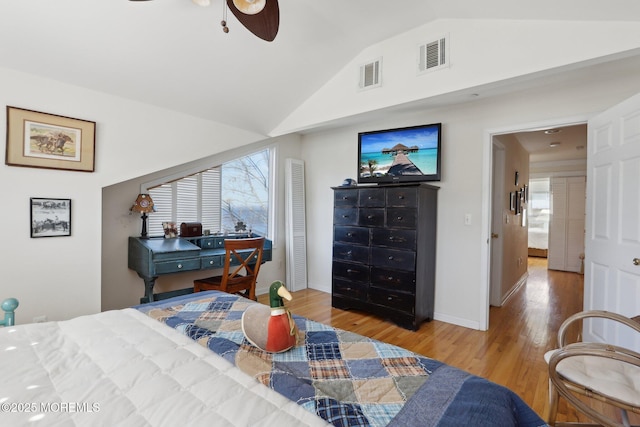 bedroom with visible vents, lofted ceiling, baseboards, and wood finished floors