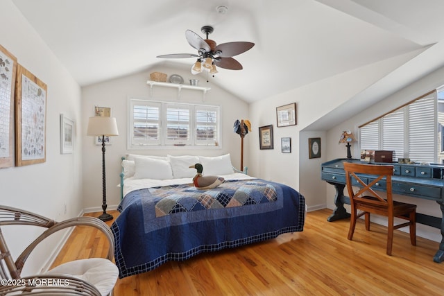 bedroom featuring light wood finished floors, ceiling fan, baseboards, and lofted ceiling