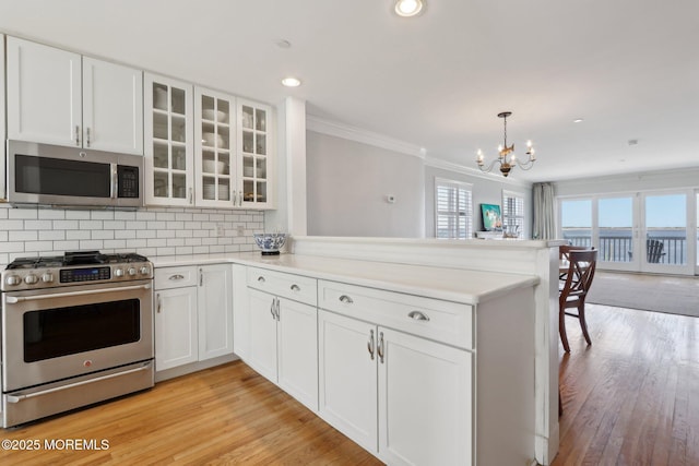 kitchen with crown molding, decorative backsplash, appliances with stainless steel finishes, a peninsula, and white cabinetry