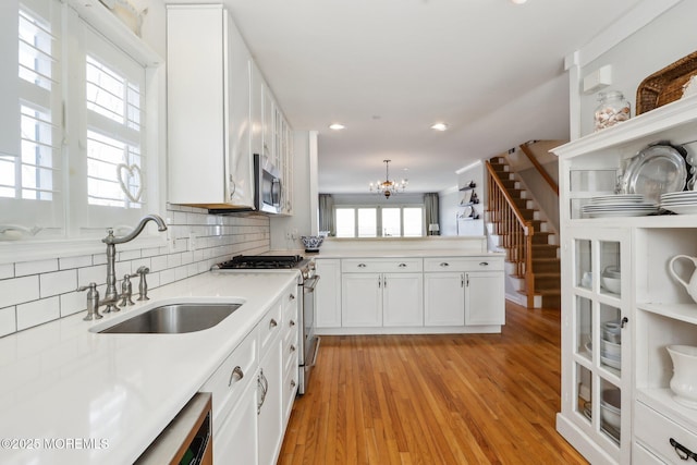 kitchen featuring light countertops, decorative backsplash, stainless steel appliances, white cabinetry, and a sink