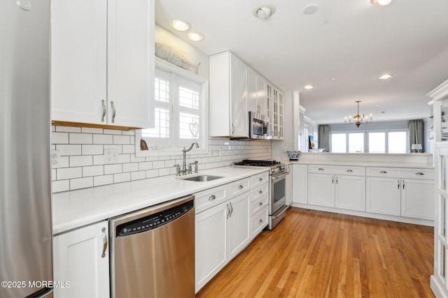 kitchen with tasteful backsplash, appliances with stainless steel finishes, white cabinetry, and a sink