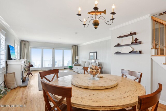 dining room with a chandelier, light wood-style floors, ornamental molding, and stairs