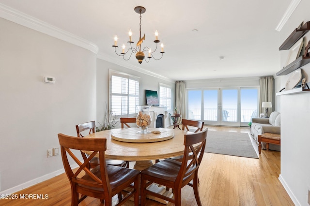 dining room featuring ornamental molding, a fireplace, light wood finished floors, baseboards, and a chandelier