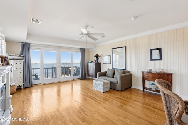 living room featuring light wood finished floors, visible vents, and ceiling fan