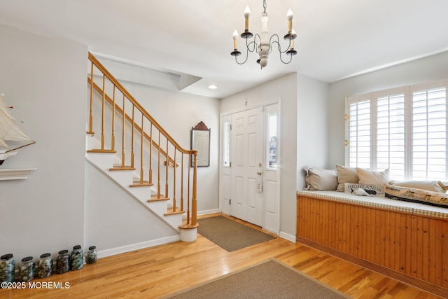 foyer entrance featuring stairway, a notable chandelier, wood finished floors, and baseboards