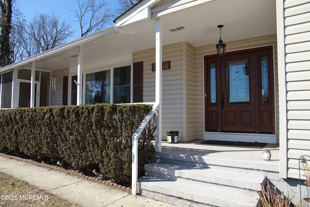 entrance to property with visible vents and a porch