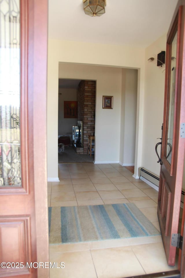 hall with light tile patterned floors, a baseboard heating unit, and baseboards