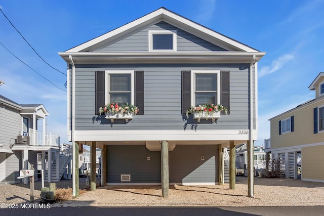 beach home featuring stairs, a carport, central AC unit, and driveway