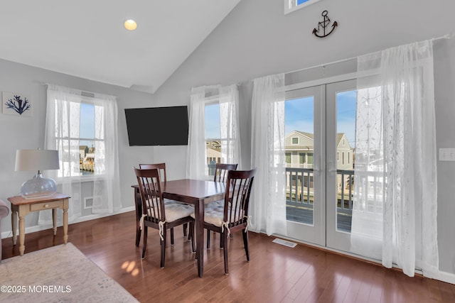 dining room featuring visible vents, high vaulted ceiling, wood finished floors, french doors, and baseboards