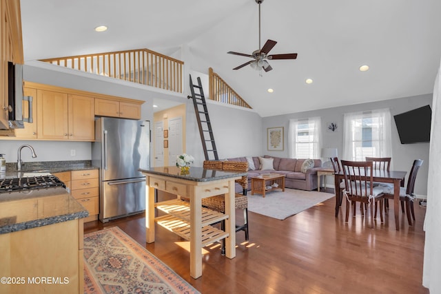 kitchen featuring light brown cabinets, dark stone counters, high end refrigerator, dark wood-style flooring, and a sink