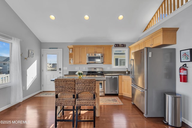 kitchen featuring light brown cabinets, appliances with stainless steel finishes, dark countertops, and lofted ceiling