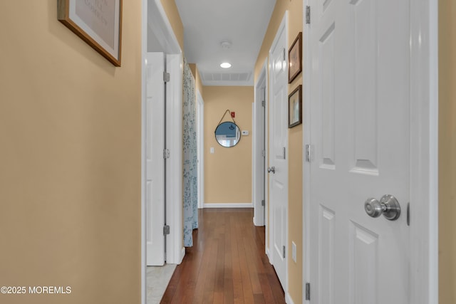 corridor featuring visible vents, baseboards, and hardwood / wood-style floors