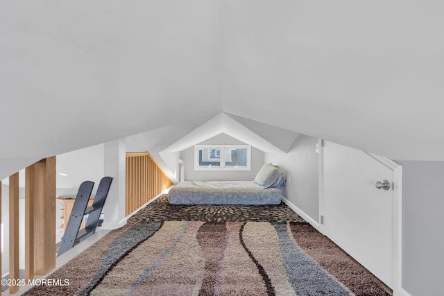 carpeted bedroom featuring baseboards and lofted ceiling